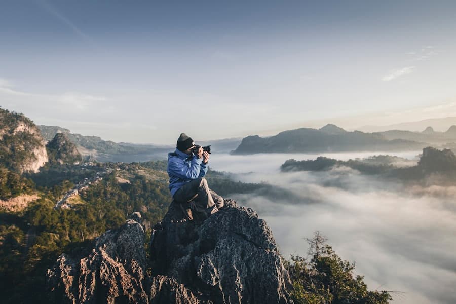 A photographer filming on a mountain ridge at sunrise
